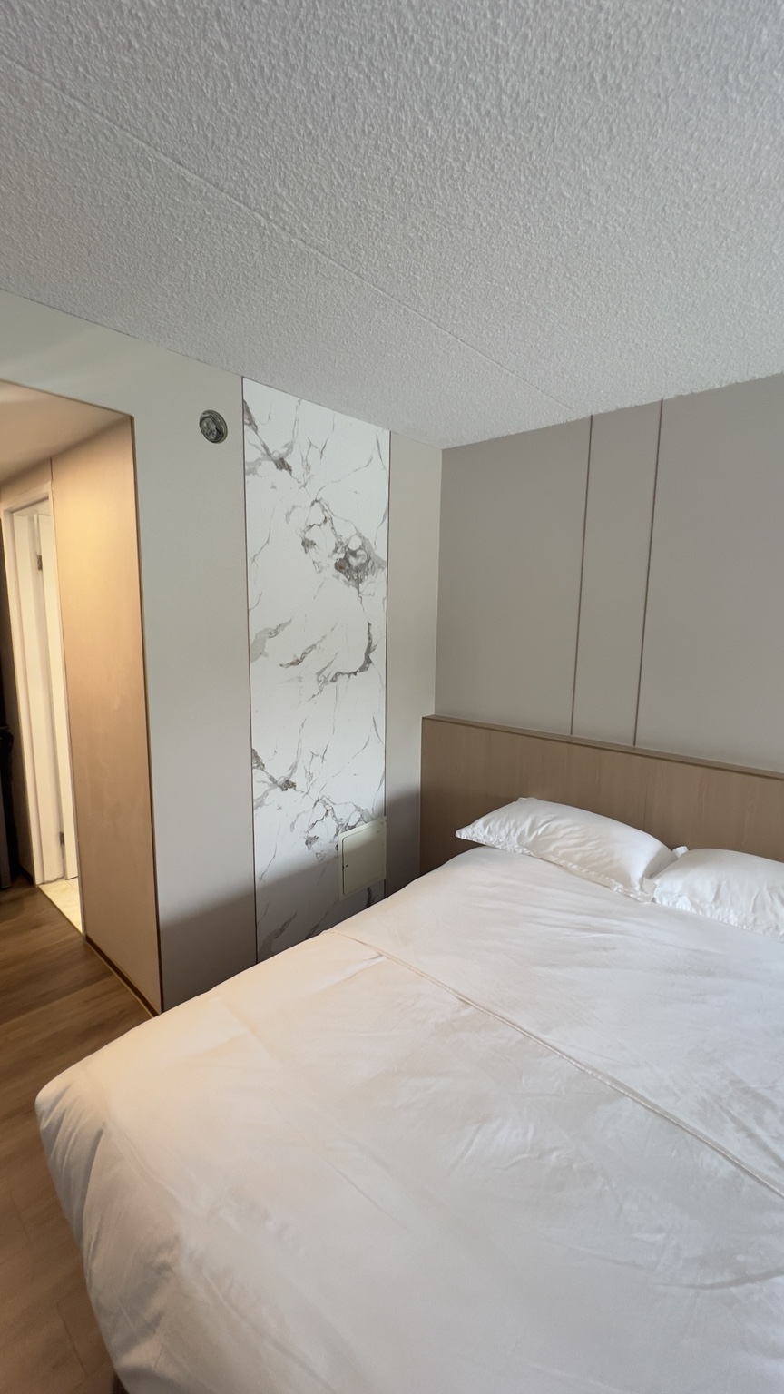 Renovations in Québec Hotel guest room with upholstered headboard and decorative wall panel